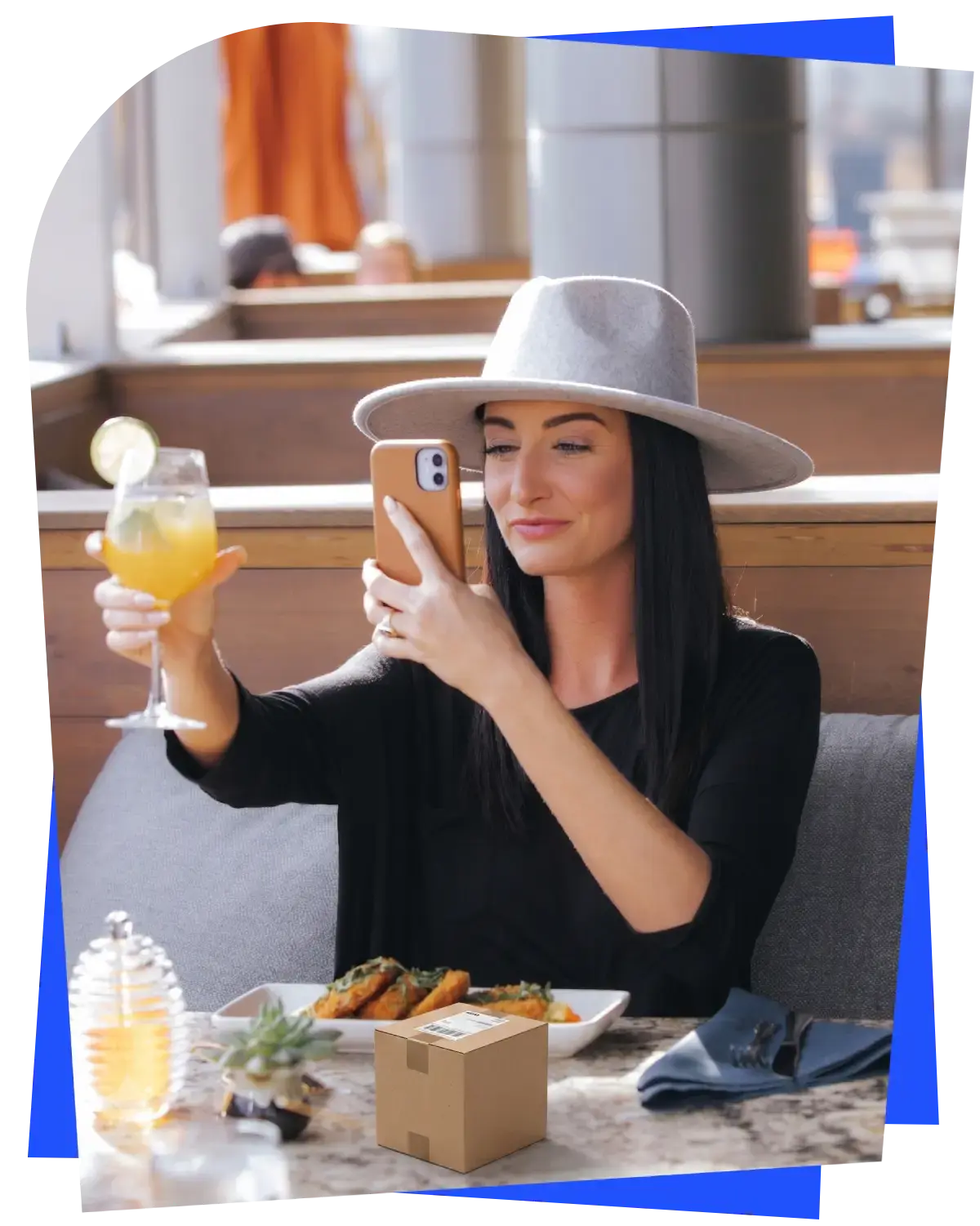 A stylish female consumer taking a smartphone photo of a cocktail and product package at a restaurant, representing engaged customer feedback..